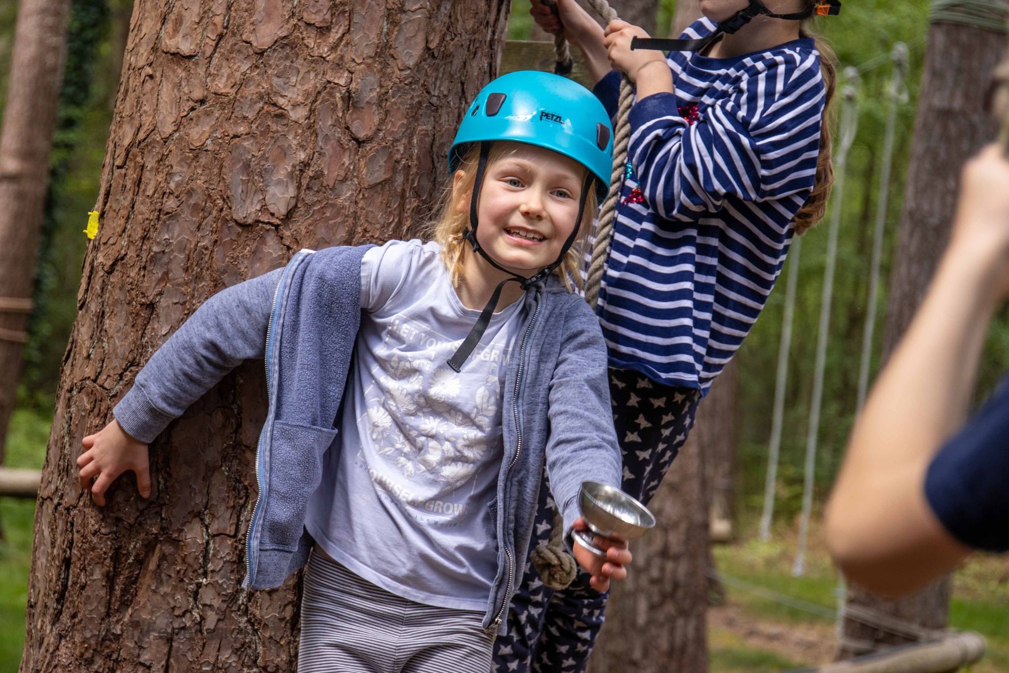 A girl clings onto a tree to complete her egg cup challenge